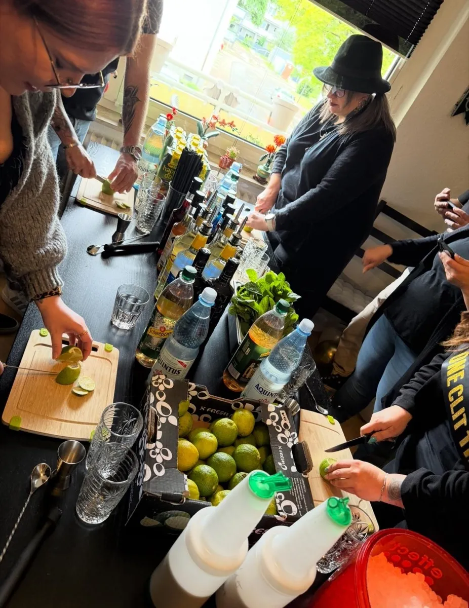 Gruppe schneidet Limetten und mixt Cocktails beim mobilen Cocktailkurs